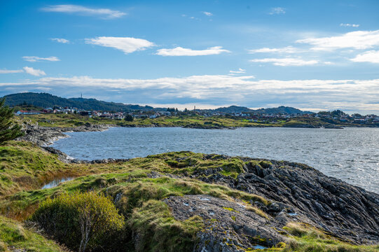 Kyststien, Haugesund, Norway, serene coastal landscape with a small town nestled among rolling hills, featuring a calm sea and lush greenery