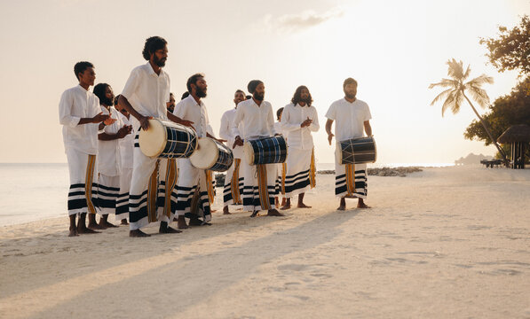 Traditional Maldivian boduberu drummers performing on a tropical beach at sunset