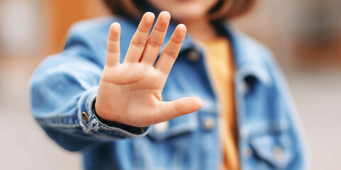 Young girl showing a stop gesture with an open palm. Symbolizing refusal, rejection, prohibition, and setting boundaries