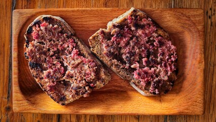 Close-up of rustic bruschetta topped with soft pork sausage, a traditional Abruzzo dish from central Italy. Served on a wooden board, symbol of authentic Mediterranean cuisine