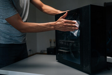 Close-up cropped shot of technician cleaning dust from computer case in dark workshop, emphasizing importance of maintenance for optimal performance and hygiene. Concept of service, cleaning PC.