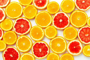 Bright top view pattern of fresh orange and grapefruit slices on a white background. Vibrant citrus texture
