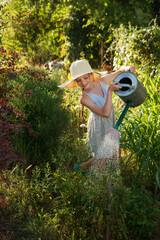Little cute girl watering trees and flowers