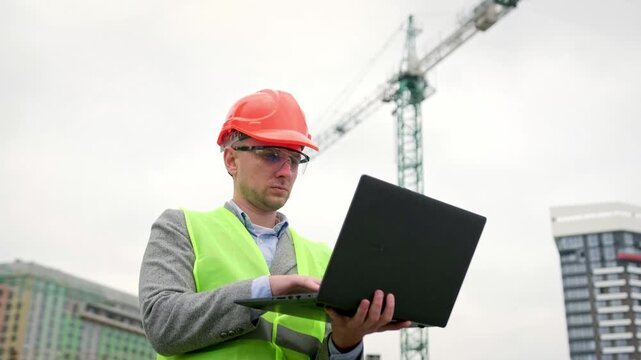 Building site inspector working on portable computer during on-site audit