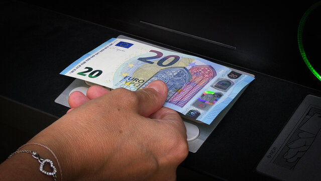 Retrait de billet de vingt euros dans un distributeur automatique bancaire en gros plan