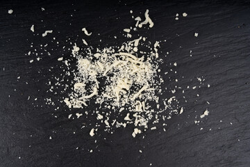 Grated mozzarella cheese on black background. Shredded mozarella texture