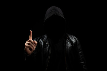 a faceless hooded man in the shadows pointing to the sky with his right hand and a black background © Alejandro Bernal