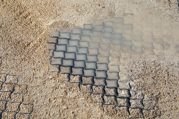 Polymer geogrid with gravel fill showing soil stabilization under wet conditions. For erosion control, permeable pavement, and road construction projects. Real photo