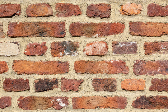Weathered red brick wall with rough surface texture natural rustic construction background pattern