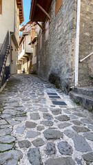 Obraz premium Charming narrow cobblestone alleyway with rustic stone buildings and blue sky