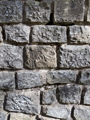 Close-up of weathered stone wall with rough texture in sunlight