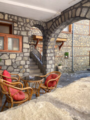 Cozy stone courtyard with rattan chairs and red cushions in rustic atmospheric setting