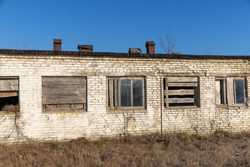 an old abandoned building made of brick in the winter, an abandoned building , the entrances to the building are boarded up