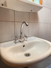 Modern white ceramic sink with stainless steel faucet in tiled bathroom