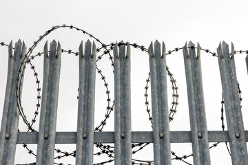 Metal Fence with Barbed Wire in Security Zone &ndash; Industrial and Safety Background