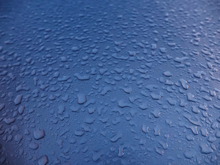 A wet surface with many small water droplets scattered across it. The droplets are of various sizes and are spread out in different directions, creating a sense of movement and fluidity