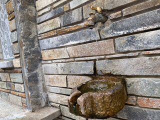 Rustic stone wall with antique water tap and weathered basin