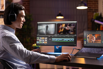 Asian sound and video editor working at apartment desk, reviewing cinematic footage for storytelling projects. Young man having productive editing session with syncing, color grading and sound design.