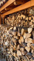 Stacked firewood logs neatly arranged outdoors under wooden shelter