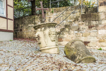 Fragmente eines Kriegerdenkmals mit Sandsteinsäule und Kreuz vor Natursteinmauer mit Treppe und Kopfsteinpflaster  am Rathaus in Lauffen am Neckar.