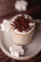 delicate ceramic mug filled with frothy cappuccino topped with chocolate sprinkles, adorned with star-shaped marshmallows on a saucer in a warm and cozy setting, pleasure, snack, ambiance, cup