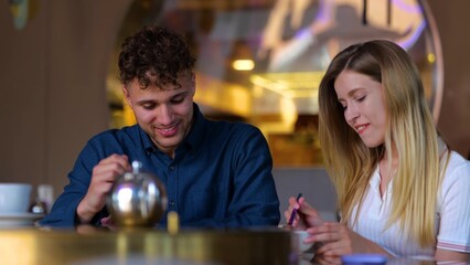 Close up of Caucasian young man and woman smiling and eating in restaurant indoors. Cheerful couple boyfriend and girlfriend together in cafeteria on a romantic date. Dating. Slow motion