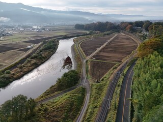 A river with a train track running alongside it. The train tracks are next to a road. The road is empty