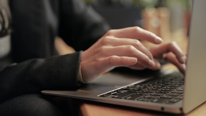 Caucasian woman working on her computer inside of contemporary place. Indoor, close up, slow motion, fingers, arms, keyboard.