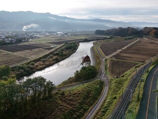 Fototapeta premium A river runs through a valley with a forest on the right side. The valley is surrounded by hills and the sky is cloudy
