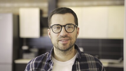 Obraz premium Smiling young man in glasses posing in the kitchen at home. Slow motion