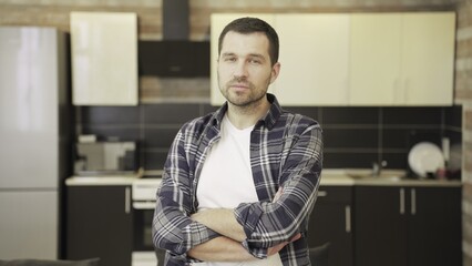 Fototapeta premium Confident man in checkered shirt standing on kitchen, looking at camera
