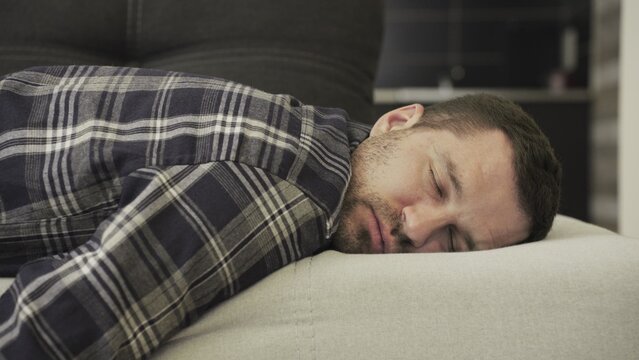 Young man in casual sleeping on couch at home. Slow motion