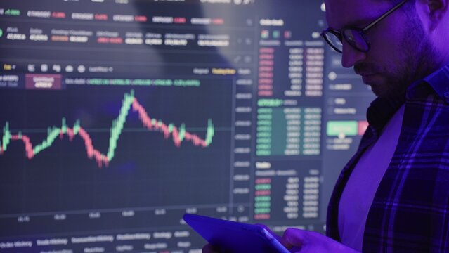 Businessman checking stock market data while using digital tablet. Slow motion