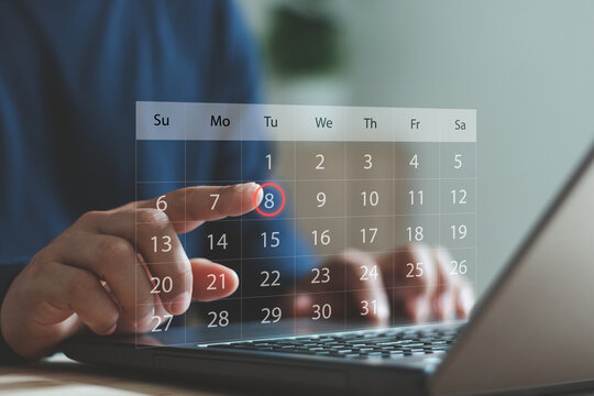 Business person using a laptop and touching a digital calendar interface, selecting a date for scheduling, event planning or time management in modern online productivity applications.