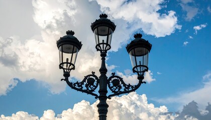 Ornate Black Street Lamp With Three Glass Lanterns Against a Dramatic Blue Sky With Puffy White Clouds and Sunlight Shining Through