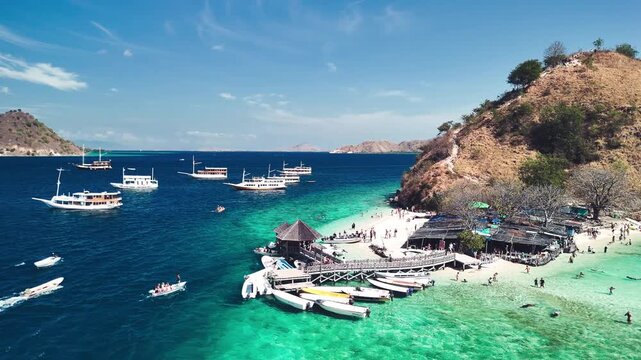 Scenic aerial panorama of Pulau Kelor Komodo showing crystal sea and snorkelers underwater
