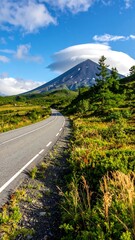 Naklejka premium Winding road leads toward a majestic mountain under a blue sky
