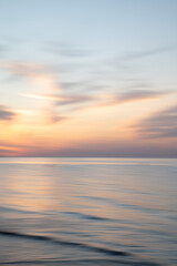 Artistic Blurred Background of Sea, Sky and clouds during a soft colours sunset. Copy space.