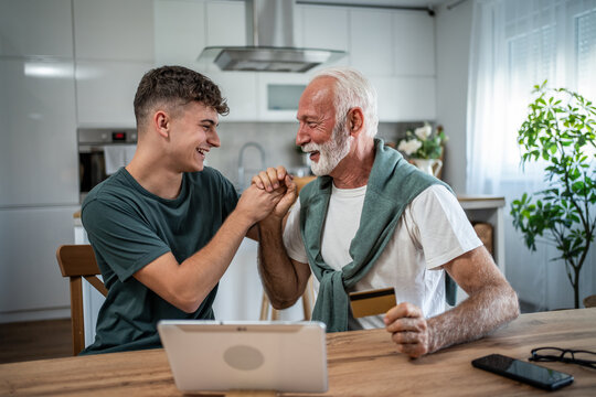 Grandfather teaching grandson online shopping using tablet and credit card
