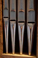 Shining organ pipes in warm church light, symbolizing sacred music and craftsmanship; vertical detail with copy space, ideal for worship and concert branding.
