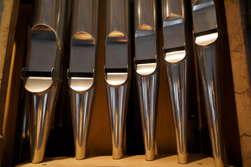 Shining organ pipes in warm church light, symbolizing sacred music and craftsmanship; vertical detail with copy space, ideal for worship and concert branding.