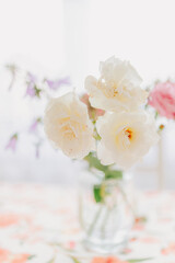 Elegant light flowers in a clear glass vase on soft background, minimal floral composition with bright petals and natural aesthetic home decor