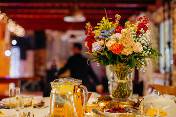 Elegant floral decorations on dining tables prepared for celebration, beautiful flower arrangements creating festive and romantic atmosphere
