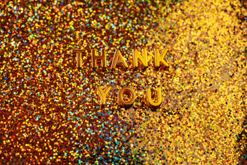 Sparkly thank you on gold glitter background.Thank you for the message.The inscription Thank you in gold letters with gold highlights on a gold background.
