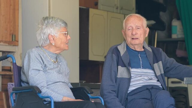 An elderly couple seated at home talking about life and experiences