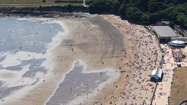 Aerial drone view of crowds of people on a busy sandy beach at Barry Island, Wales