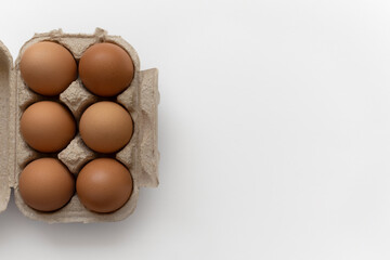 Top view of half dozen brown eggs in open paper pulp egg carton on right side, isolated, white background with empty space on left, close-up concept of freshness and natural food © DariaR