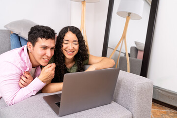 Young couple enjoying digital content on laptop at home