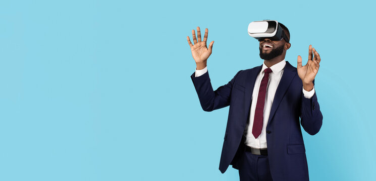 Excited Black Businessman Wearing VR Glasses And Suit Standing On Blue Background, Happy African American Male Enjoying Virtual Reality Experience And Modern Technologies, Panorama With Copy Space