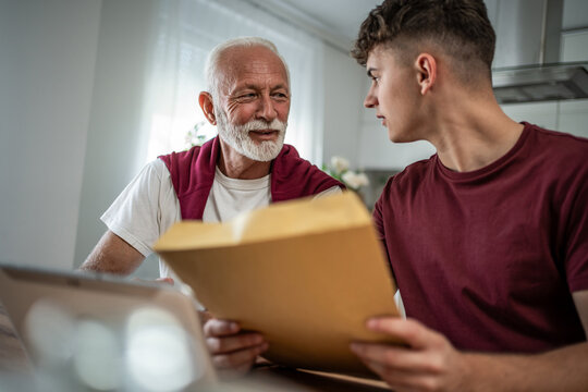 Grandfather and grandson discussing important paperwork at home - Powered by Adobe
